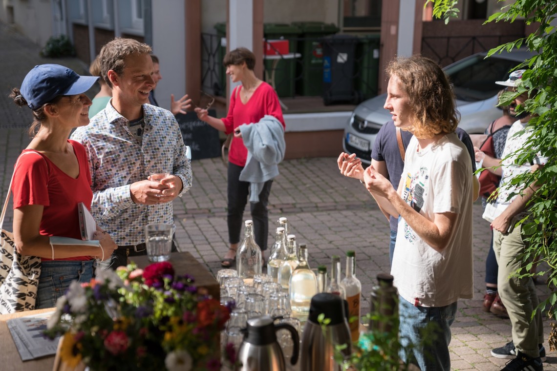 Menschen im Gespräch, im Vordergrund Getränke und Blumen | © Gunnar Fuchs
