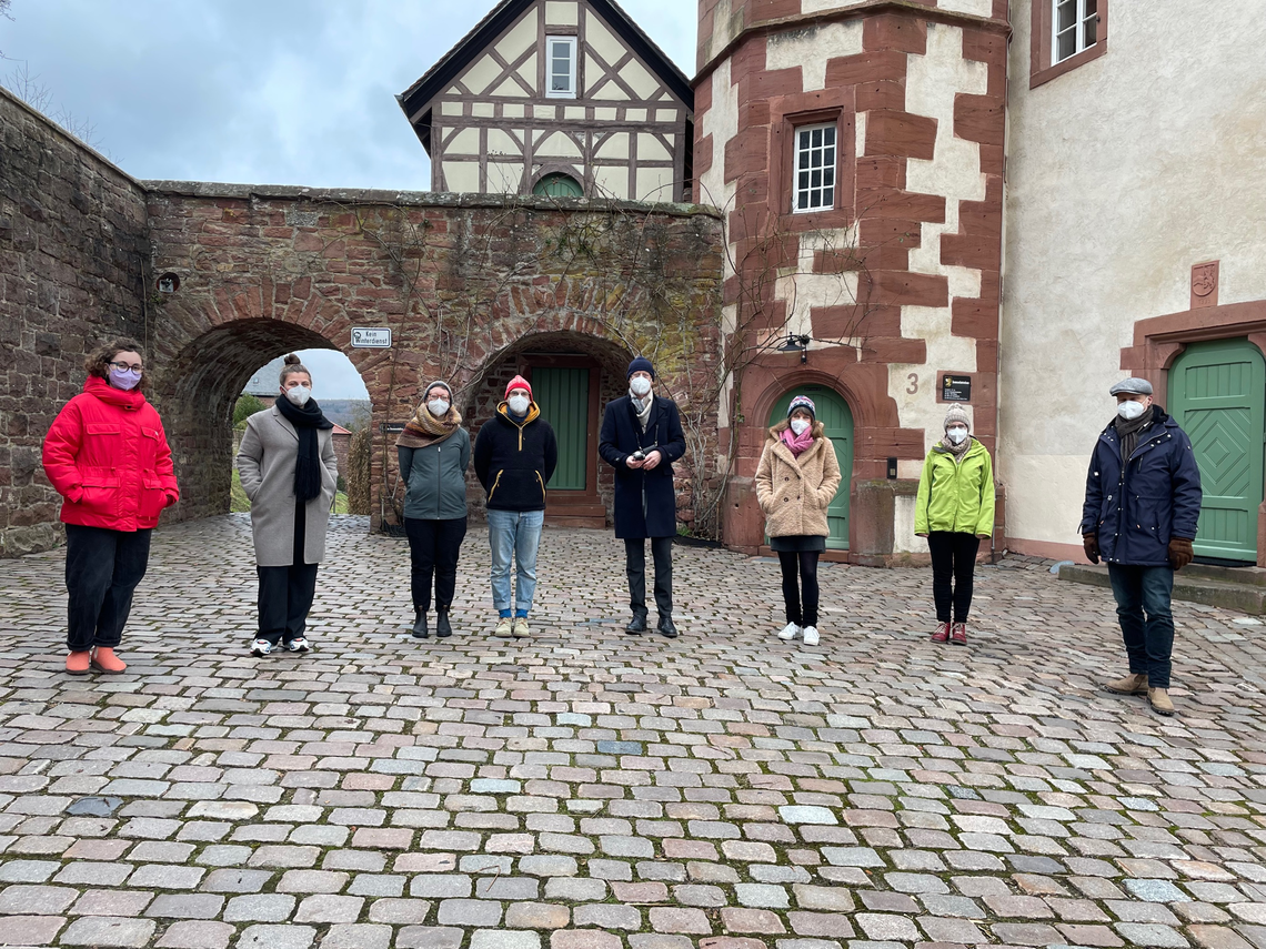 Acht Personen mit FFP2-Masken stehen in einer Reihe vor dem Gebäude der Burgfeste Dilsberg | © MRN GmbH