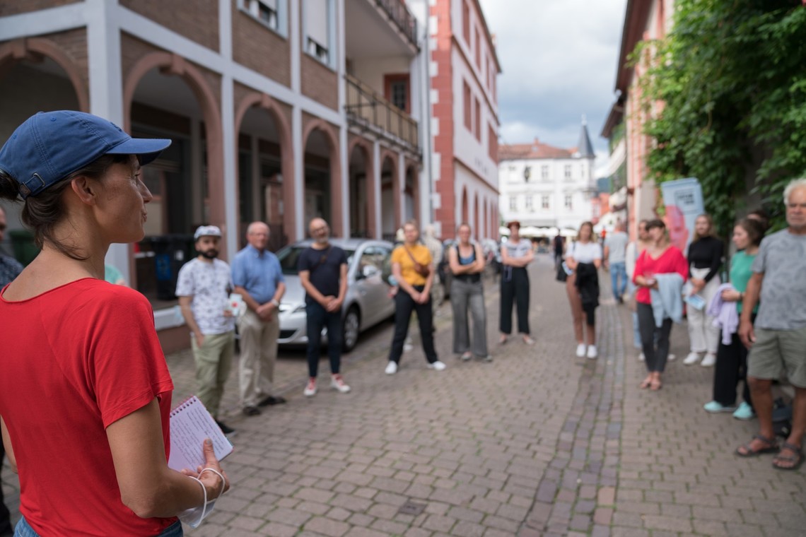 Menschen stehen im Kreis und hören einer Frau zu | © Gunnar Fuchs