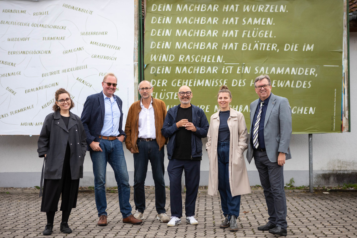 sechs Personen posieren für ein Gruppenfoto vor grün-weißen Plakaten mit Schrift der Künstler:innen | © © Arthur Bauer