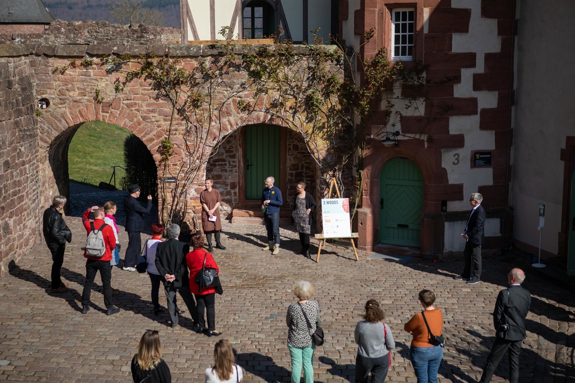 Menschen stehen als Publikum vor Personen, die miteinander sprechen, draußen  | © Elisa Berdica