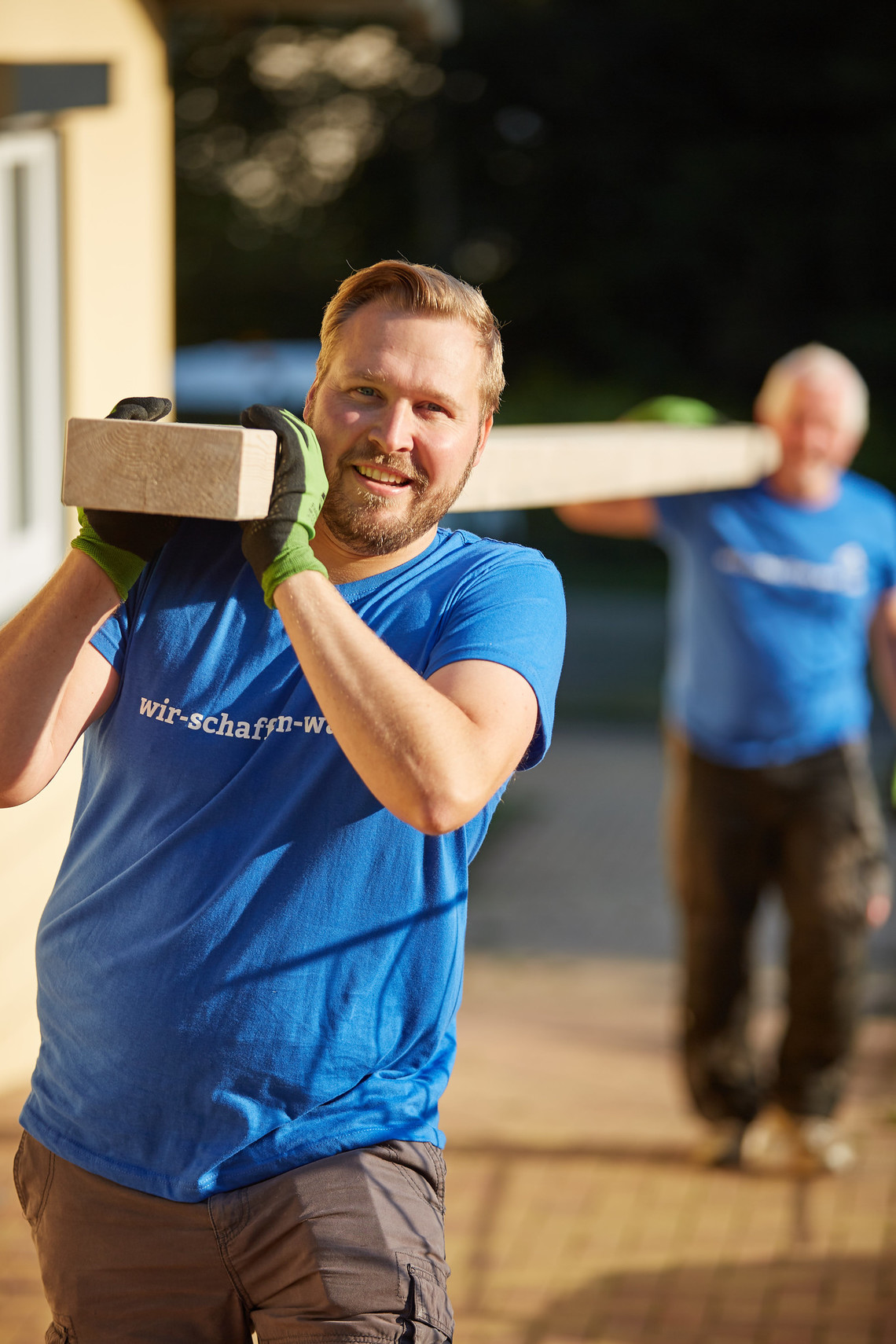 Personen tragen gemeinsam einen Holzbalken  | © MRN GmbH