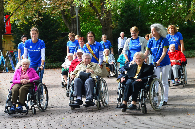 Personen schieben ältere Personen im Rollstuhl | © Rhein-Neckar