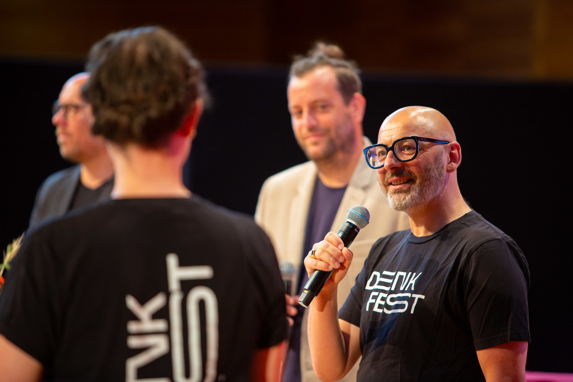 Ein Moderator mit Mikrofon im Fokus | © Thomas Häfner
