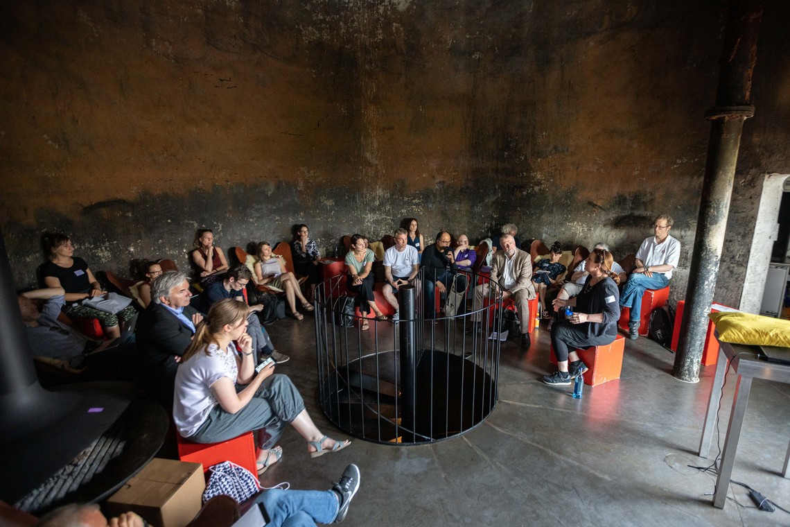 Personen sitzen in einem runden Zimmer im Kreis und sprechen | © Arthur Bauer