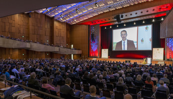 Voller Veranstaltungsraum auf der Bühne spricht jemand | © MRN 