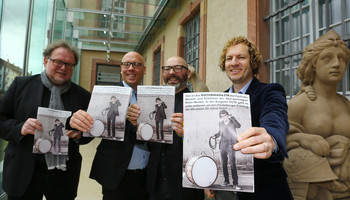 Vier Männer stehen draußen und halten alle das Kulturmagazin in die Kamera | © MRN GmbH