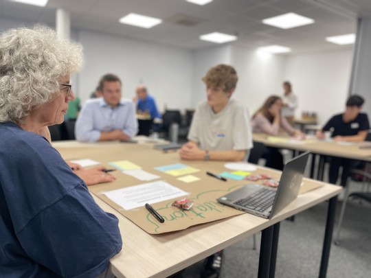 Ältere Frau und zwei Männer sitzen an einem Tisch. Vor ihnen Post-Its und Stifte | © VRRN / LH