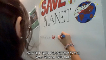 Mädchen schreibt etwas an ein Flipboard "Was können wir tun? Save the Planet" | © Girls Go Movie / Don‘t say I didn‘t warn you